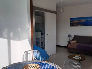 A room with a bed, a chair, a table, a sofa, and a painting on the wall.
