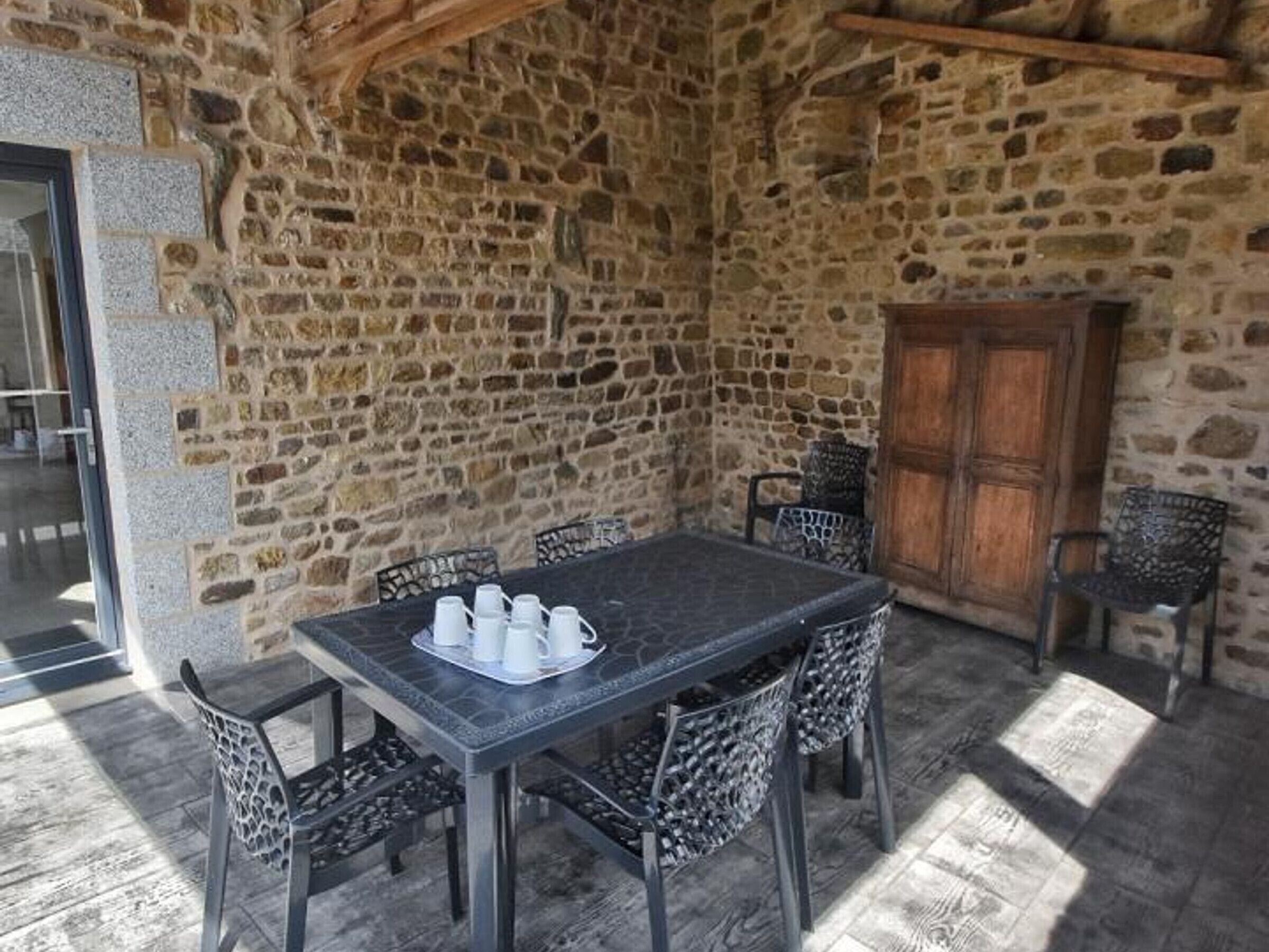 A stone-walled outdoor dining area with a table and chairs.