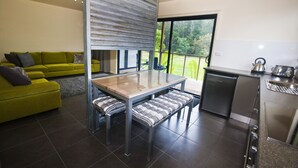 A modern kitchen with a dining area, a green sofa, and a view of the outdoors. - Tyenna River Cottage (Tyenna)