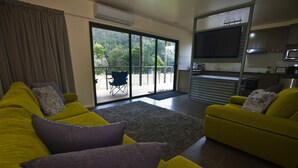 A modern living room with two yellow sofas, a grey rug, and a balcony with a chair. - Tyenna River Cottage (Tyenna)