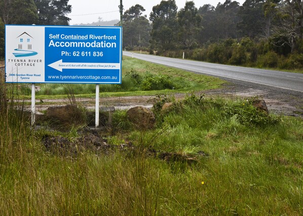 A sign for Tyenna River Cottage, a self-contained riverfront accommodation with a contact number and website. - Tyenna River Cottage (Tyenna)