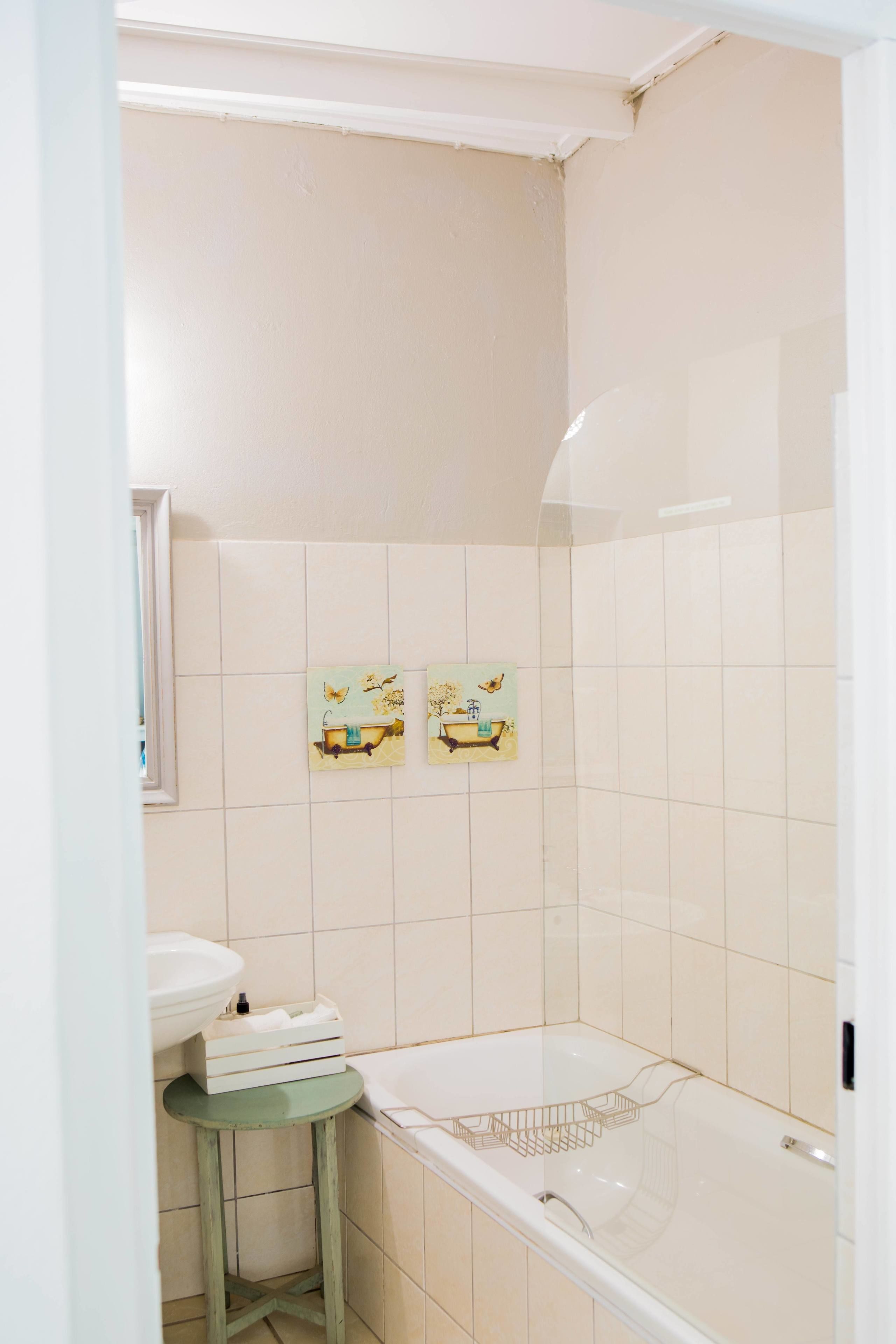 A bathroom with a bathtub, a sink, and two wall-mounted artwork pieces.