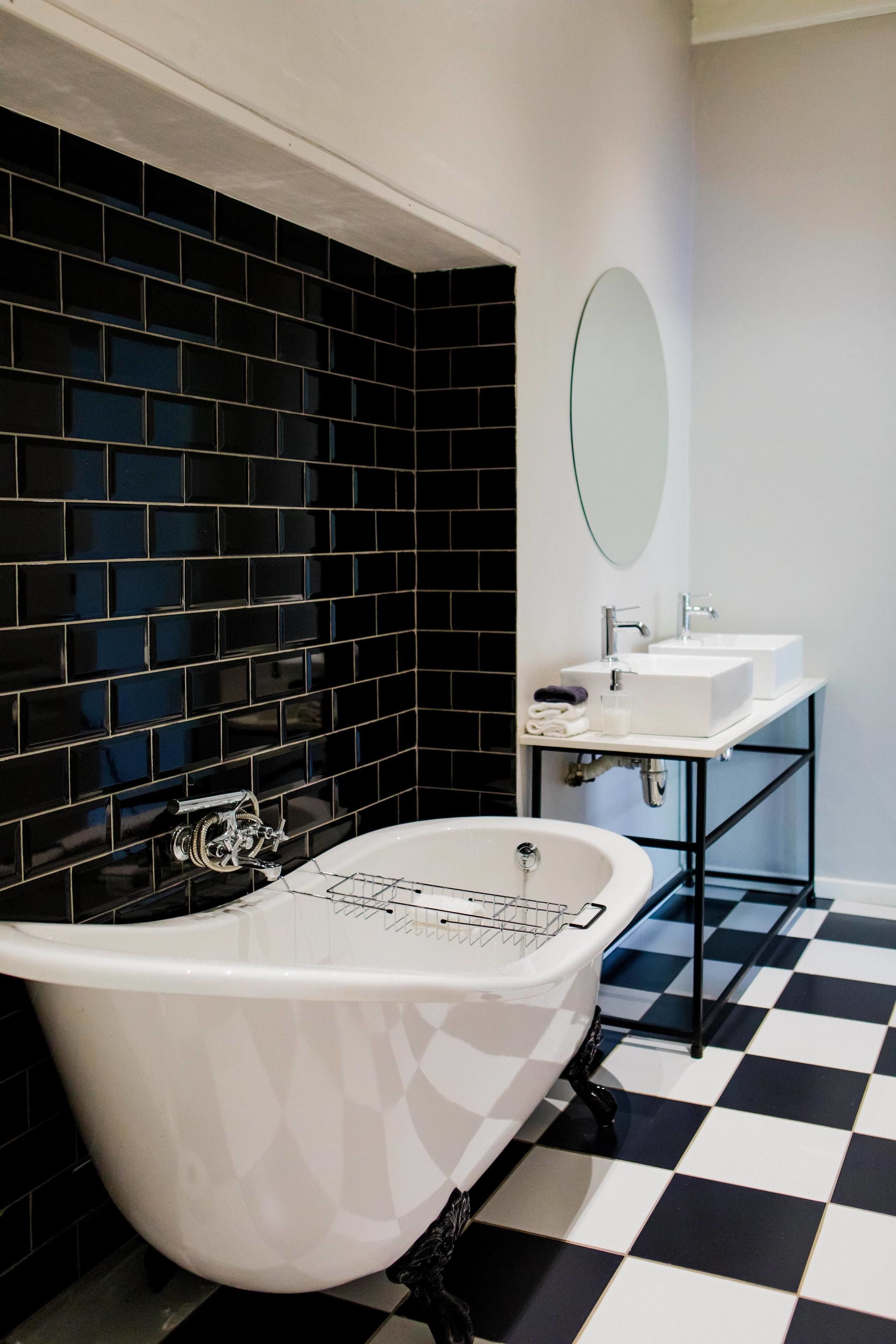 A bathroom with a freestanding bathtub, two sinks, a mirror, and black and white checkered flooring.