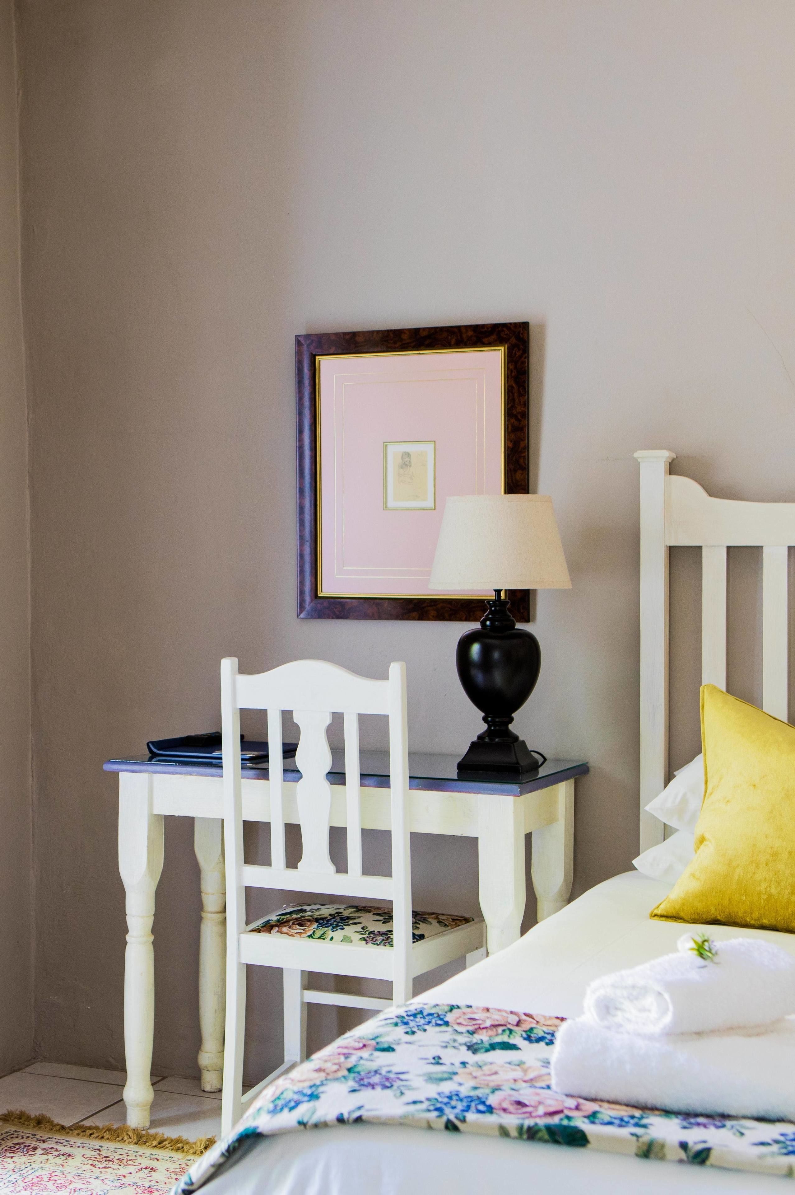 Une chambre à coucher avec un lit, une chaise, un bureau et une lampe.