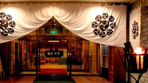A hotel entrance with a traditional design, featuring a red carpet and decorative wall panels.