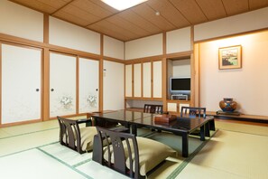 A traditional Japanese-style room with tatami flooring, a low table, and wooden chairs. - Hotel Sakadojo Minamiuonuma (Minamiuonuma)