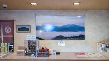 A reception area with a large poster of a mountain landscape, a PayPay payment terminal, and a small shrine with offerings.