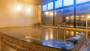 A heated indoor pool with a glass wall and metal railings.