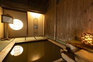 A traditional Japanese onsen with a wooden interior, a tatami mat floor, a wooden bench, and a lantern. - Hotel Sakadojo Minamiuonuma (Minamiuonuma)