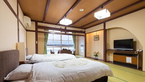 A hotel room with two beds, a television, and a view of the sea.