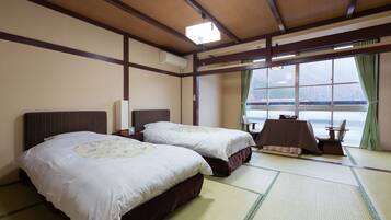 A hotel room with two beds, a table, and a view of the sea.