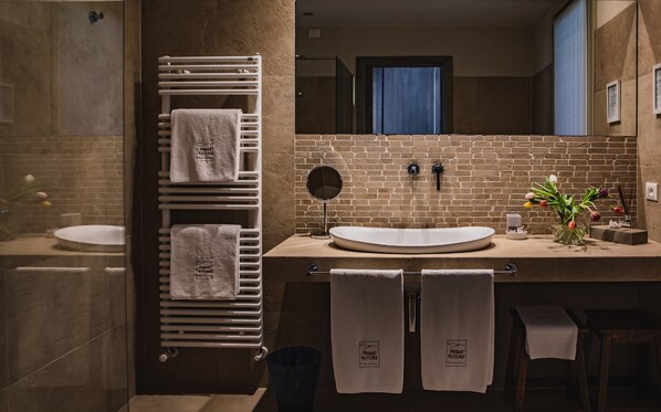Un baño moderno con un espejo grande, dos lavamanos y un perchero con varias toallas.