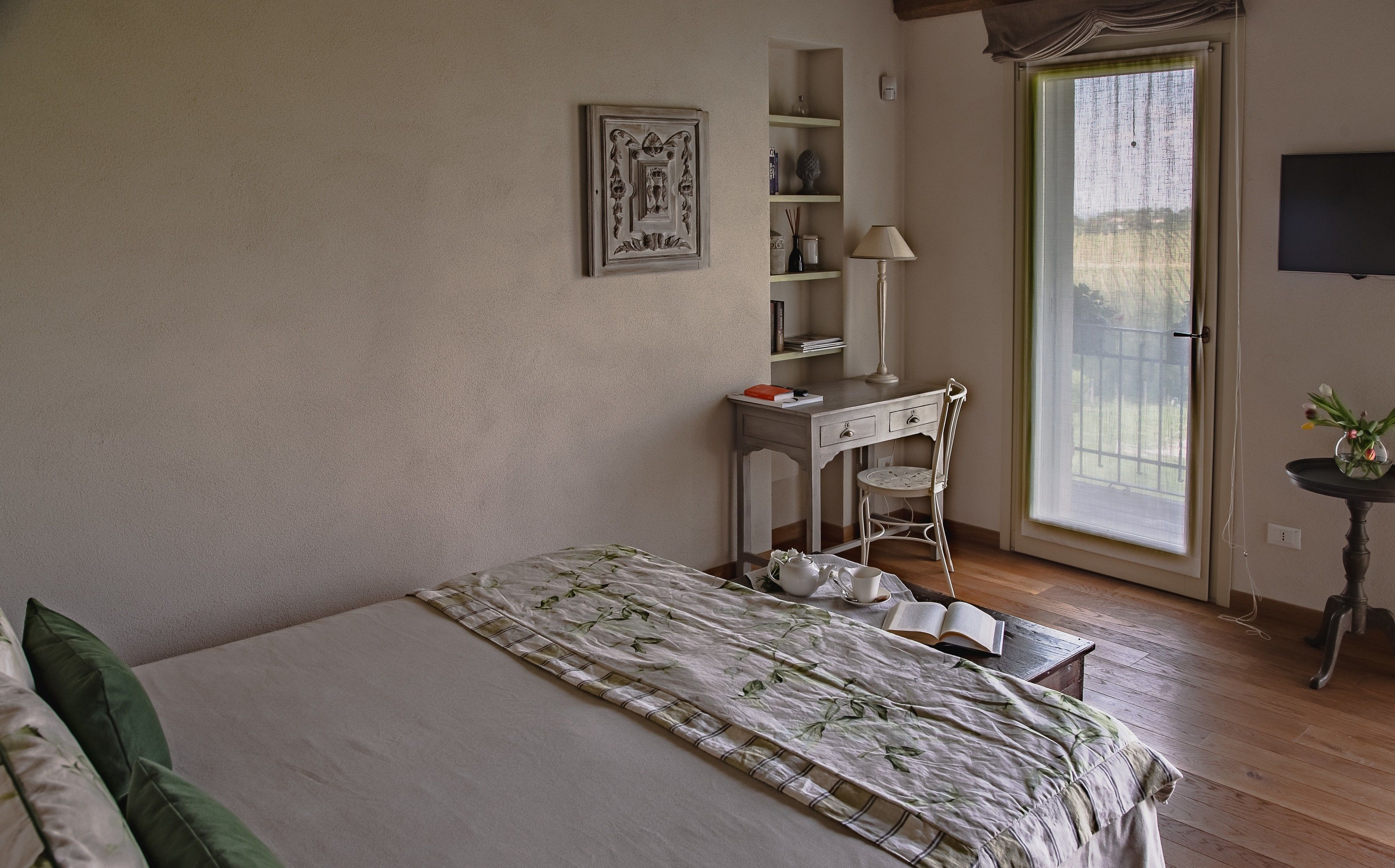 A bedroom with a bed, a desk, a chair, a window, and a television.