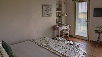 A bedroom with a bed, a desk, a chair, a window, and a television.