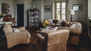 Un salón acogedor con muebles de cuero, una estantería y una ventana con luz natural.