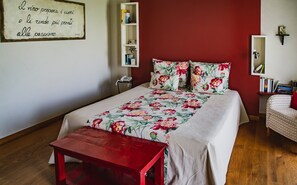 A bedroom with a floral bedspread, a red bench, a bookshelf, and a motivational quote on the wall. - Prime Alture Wine Resort (Casteggio)