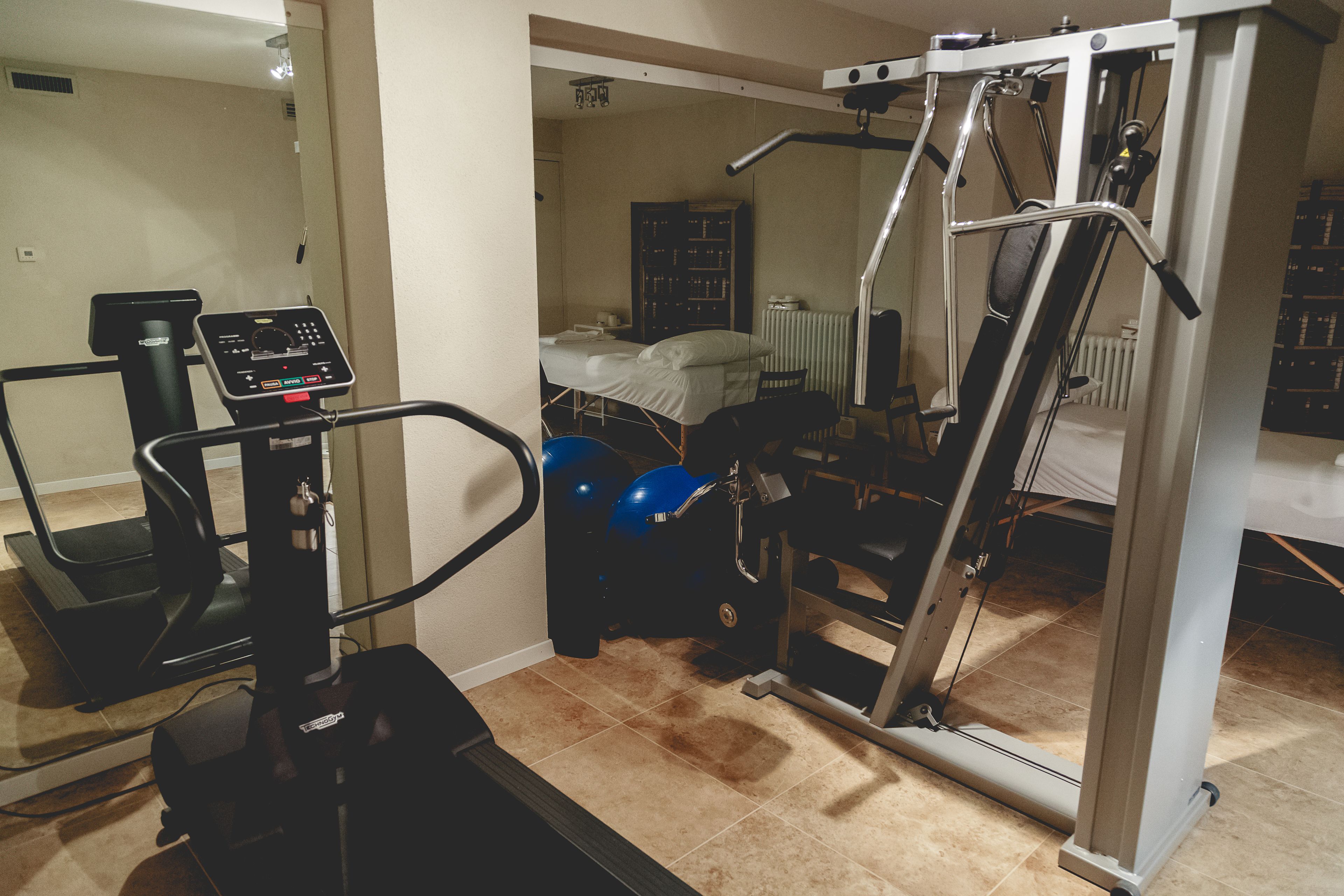 A home gym with a treadmill, elliptical, and weight machine.