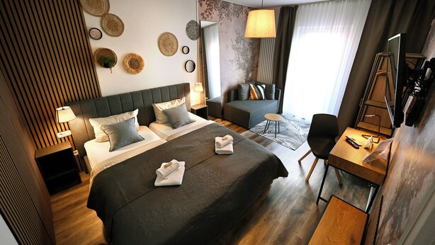 Una habitación de hotel con cama, sofá, escritorio, silla y televisor.