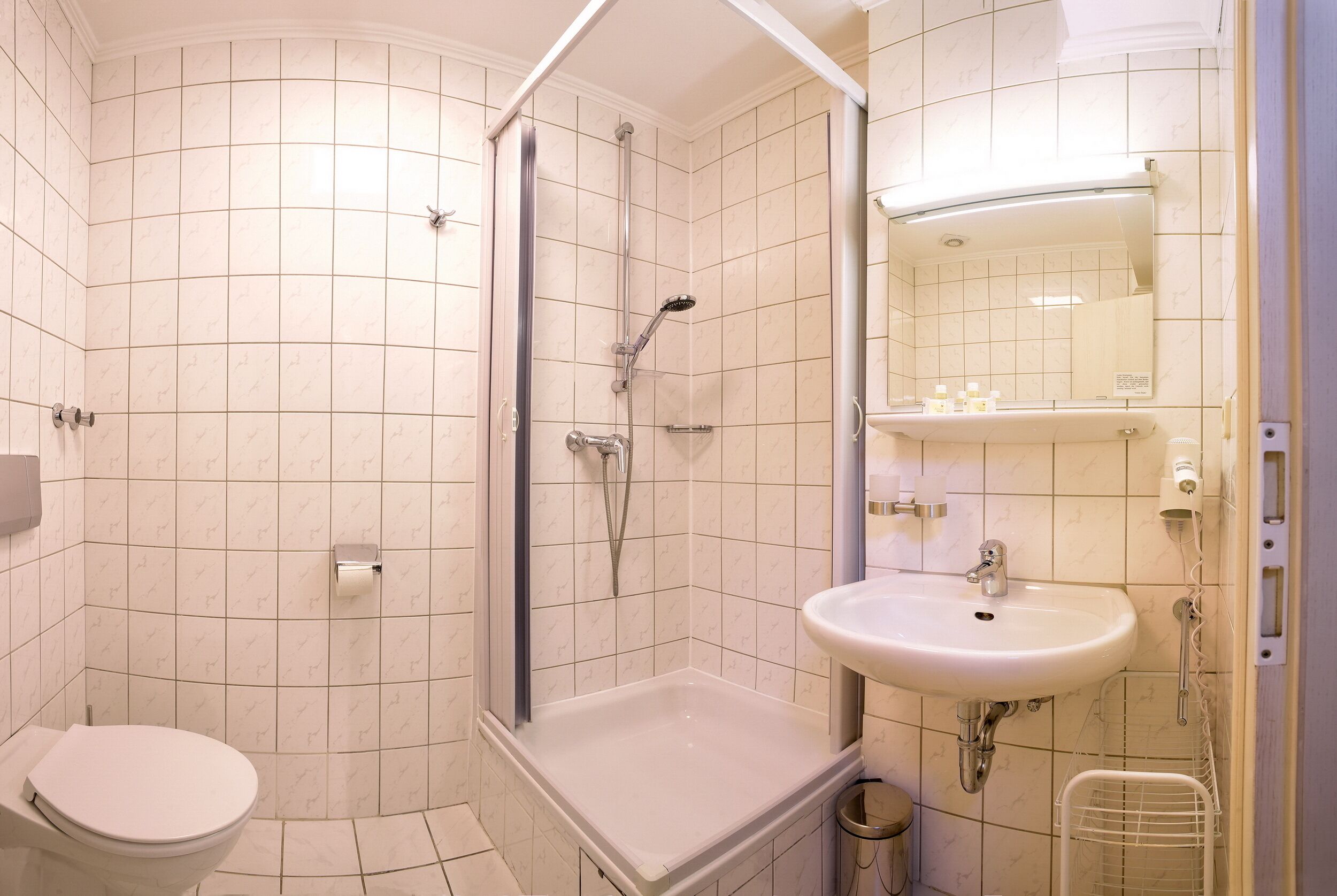 A bathroom with a toilet, shower, and sink.