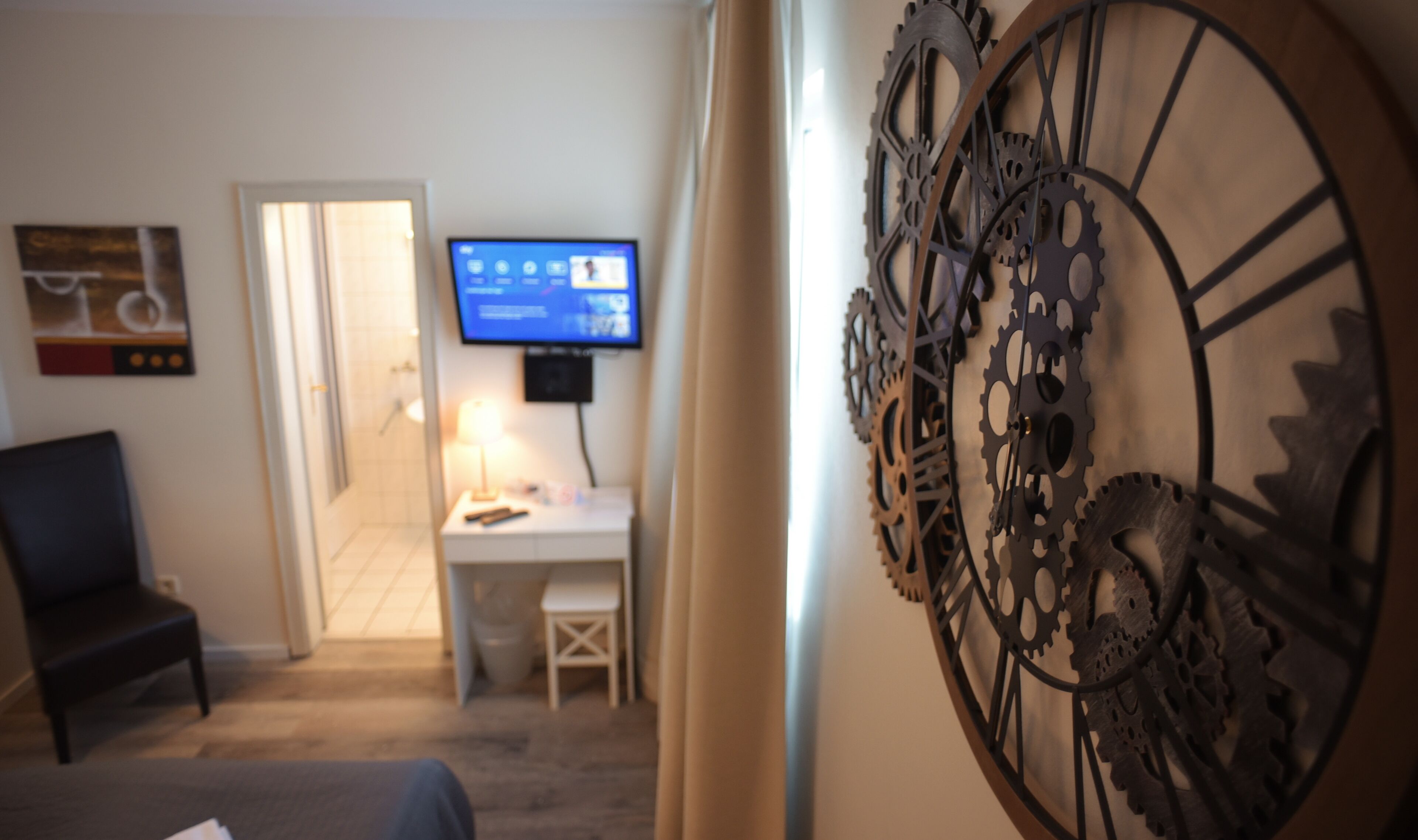 Habitación de hotel con escritorio, silla, televisión y decoración en la pared.