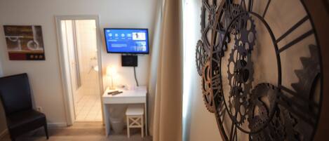Habitación de hotel con escritorio, silla, televisión y decoración en la pared.
