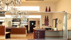 Un área de bar moderna con mostrador de madera, una lámpara de araña y un reloj en la pared.