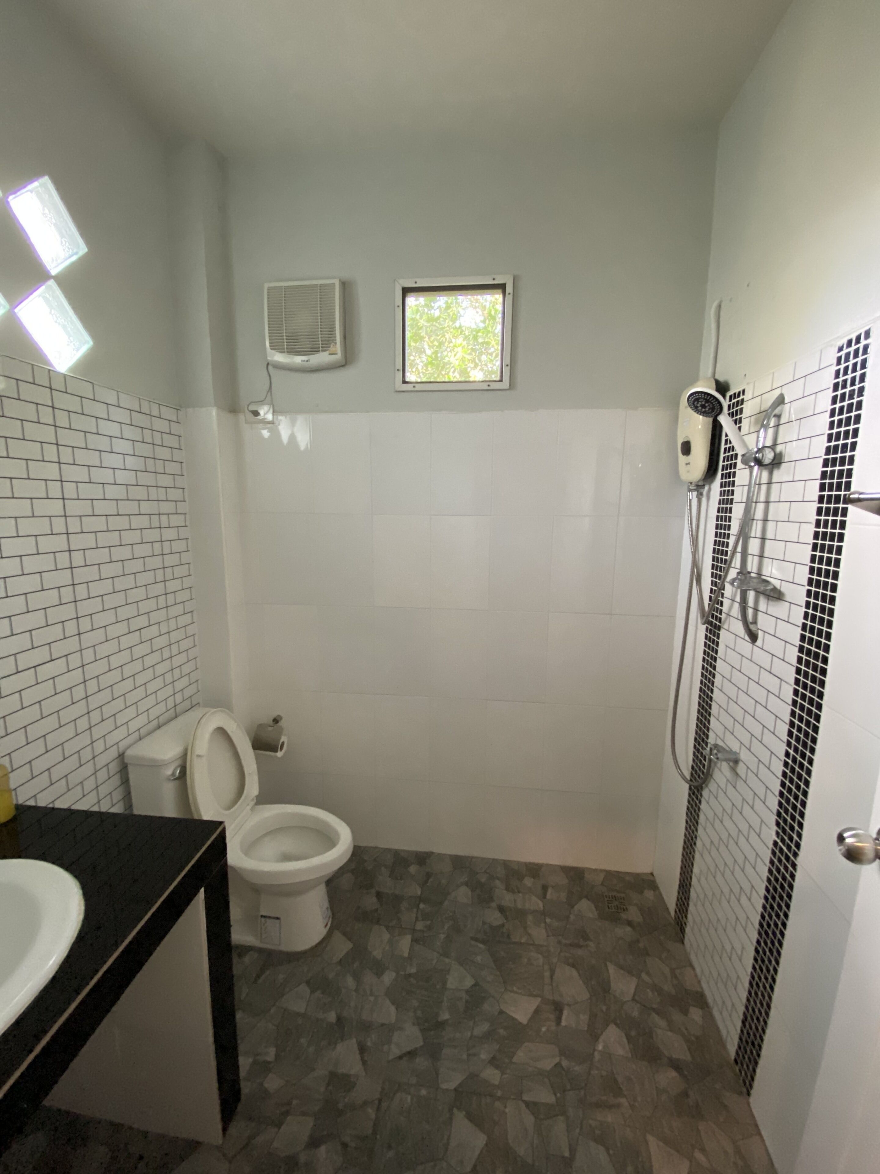 Une salle de bain avec des toilettes, une douche et une petite fenêtre.