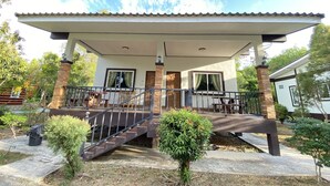A two-story house with a covered porch, a staircase, and a small garden area.