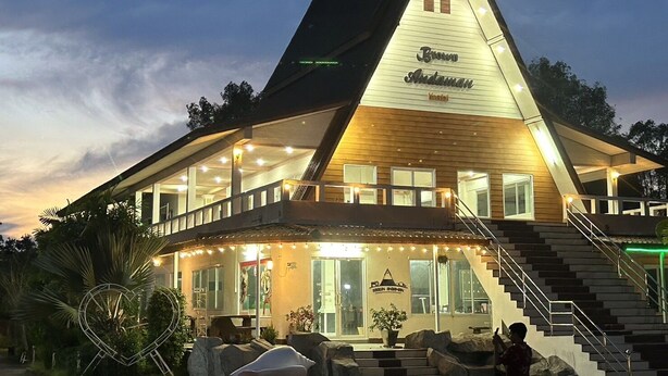 A modern hotel with a prominent triangular roof, large windows, and a well-lit entrance.
