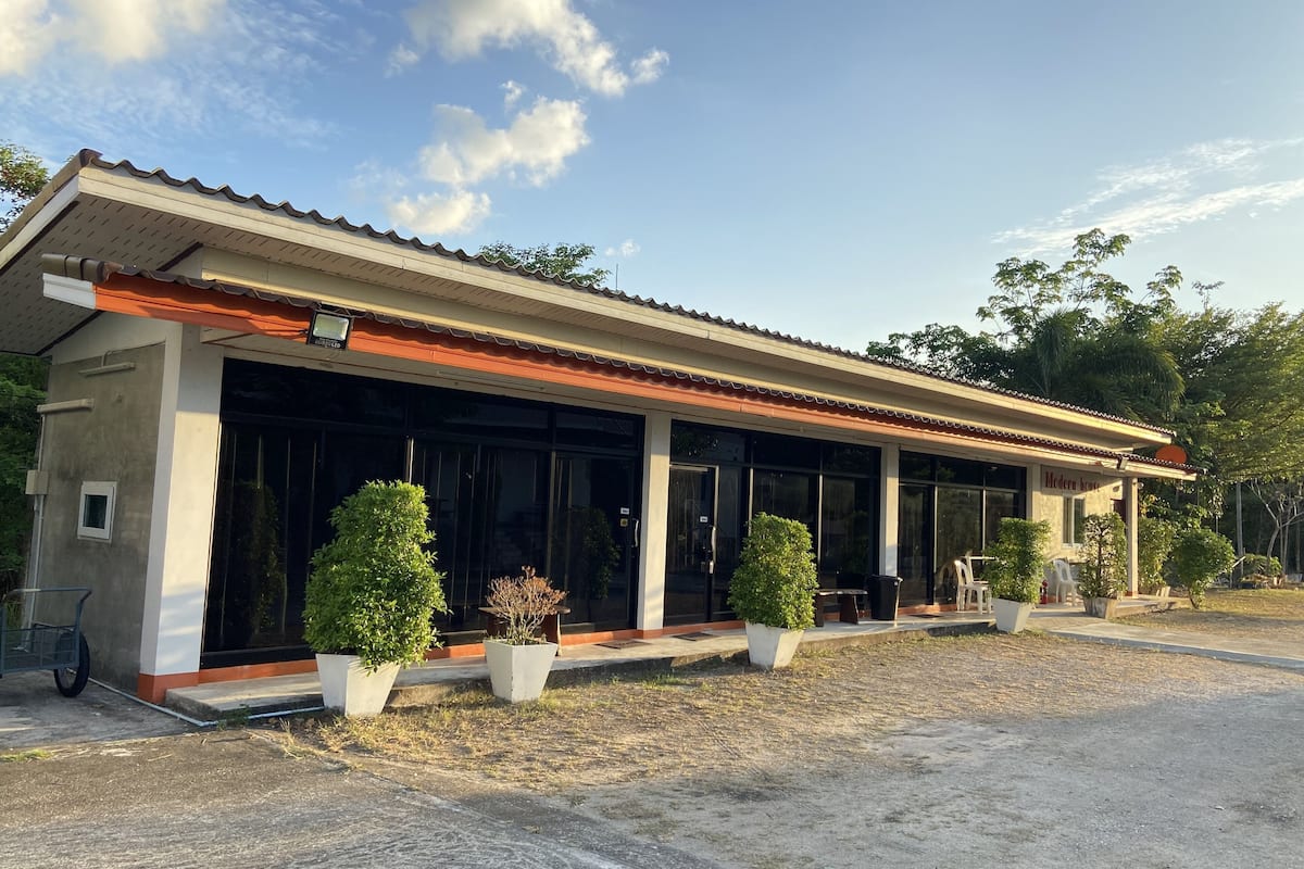 Una casa moderna con un amplio frente de vidrio, techo de tejas y plantas en macetas en el jardín delantero.