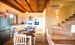 A modern kitchen with a built-in oven, a refrigerator, and a dining area with a wooden table and chairs.