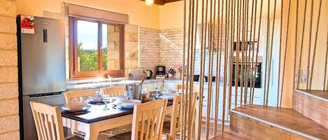 A kitchen with a dining table set for four, a refrigerator, and a window with a view of greenery.