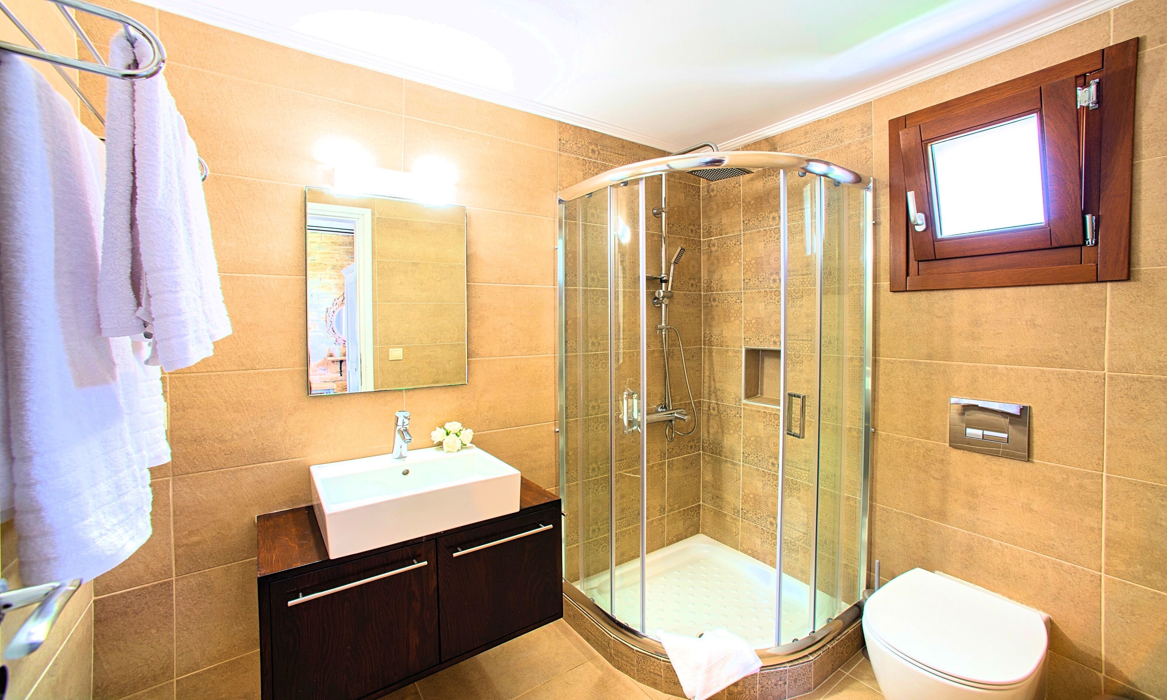 A bathroom with a glass-enclosed shower, a sink, and a toilet.