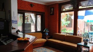 A cozy living area with a brick wall, a sofa, a coffee table, and a window with blinds. - Mandap Hotel (Kathmandu)