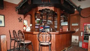 A bar area with a wooden counter, two metal chairs, and a red vending machine. - Mandap Hotel (Kathmandu)