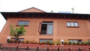 A two-story building with a brick facade, multiple windows, and a balcony with potted plants. - Mandap Hotel (Kathmandu)