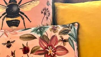 Un sofá con un cojín floral y uno con diseño de abeja.