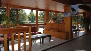 Un intérieur en bois avec un banc, des tables et une vue sur l’extérieur.