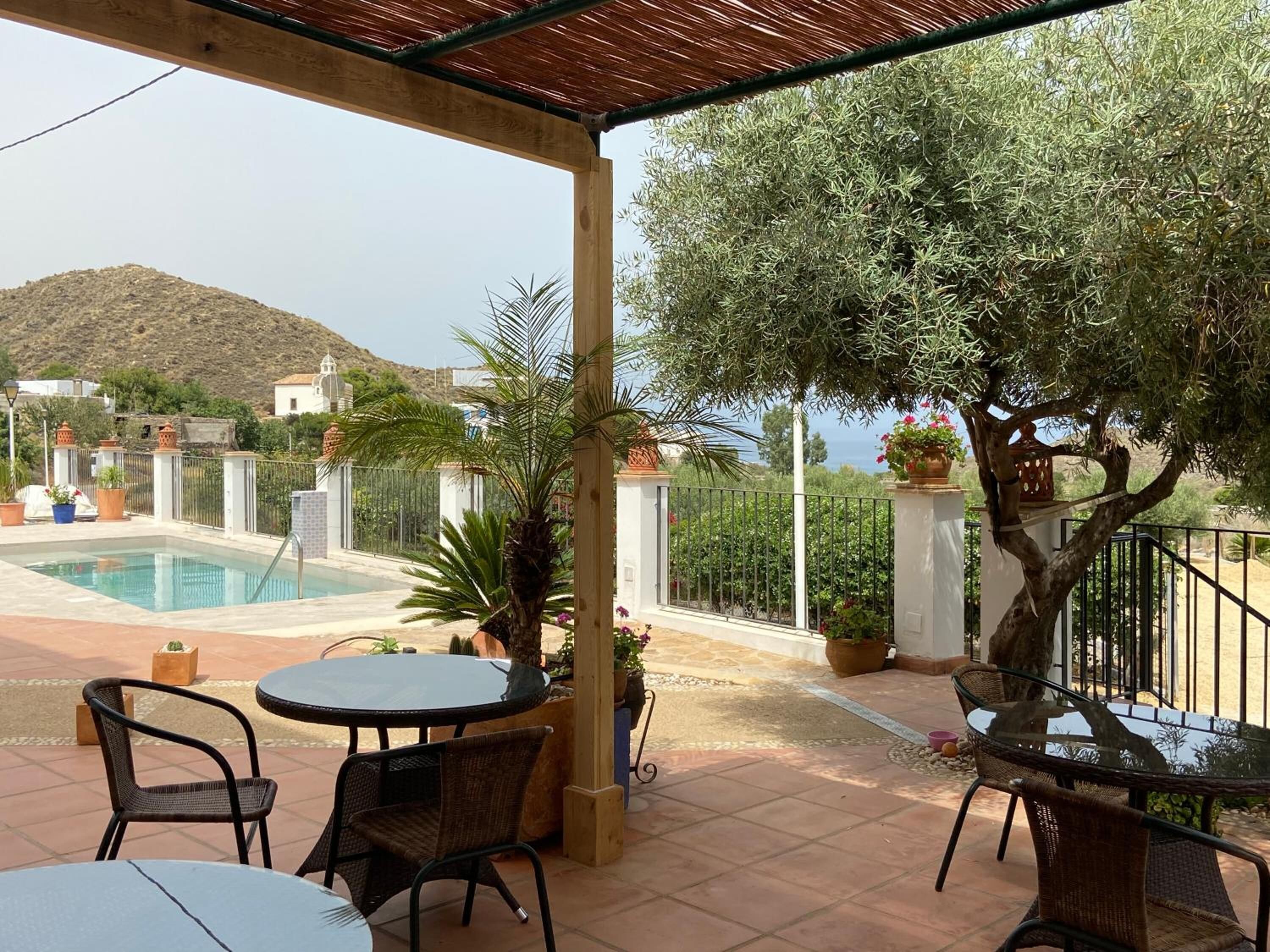 A covered outdoor area with a pool, seating, and potted plants.