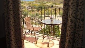 A balcony with a wicker chair and a small round table, overlooking a scenic landscape with hills and a view of the sea. - Casa Rural Mi Abuela María - Adults Only (Mojacar)