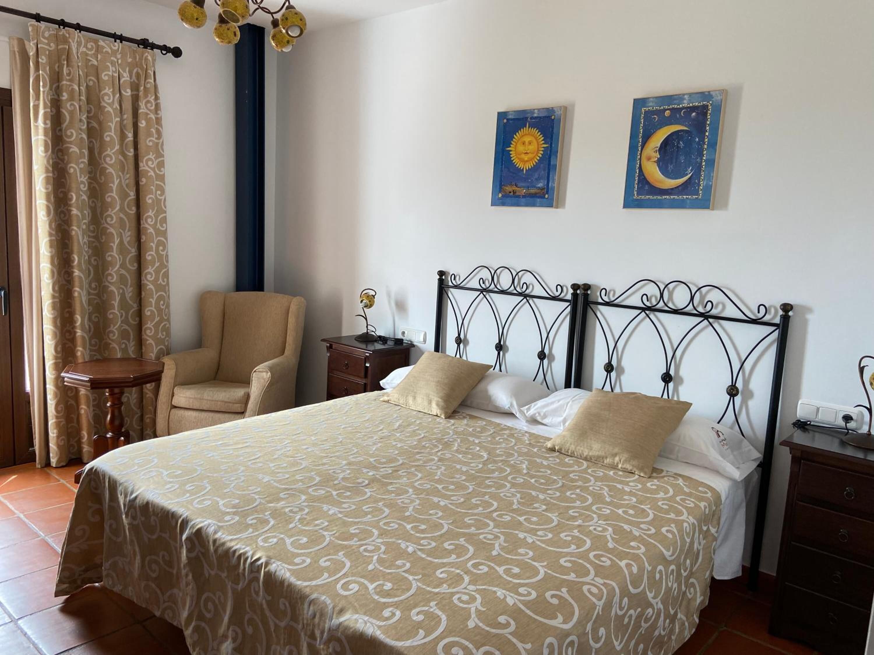 A bedroom with a bed, a chair, a nightstand, and two wall art pieces.