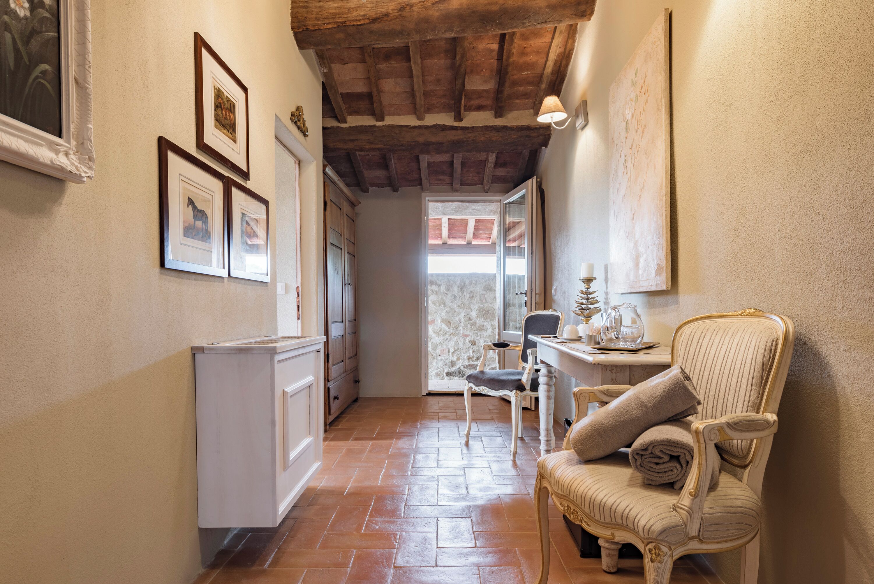A narrow hallway with a tiled floor, a radiator, and a chair with a rolled-up towel.