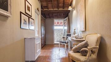 A narrow hallway with a tiled floor, a radiator, and a chair with a rolled-up towel.