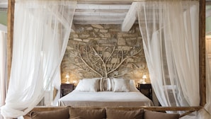A bed with a canopy, stone wall, and two bedside tables with lamps. - Dimora Santa Margherita - Boutique Hotel (Cinigiano)