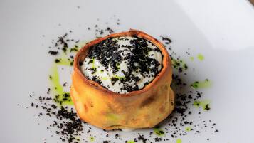 A dessert in a bowl on a plate with green and black toppings.