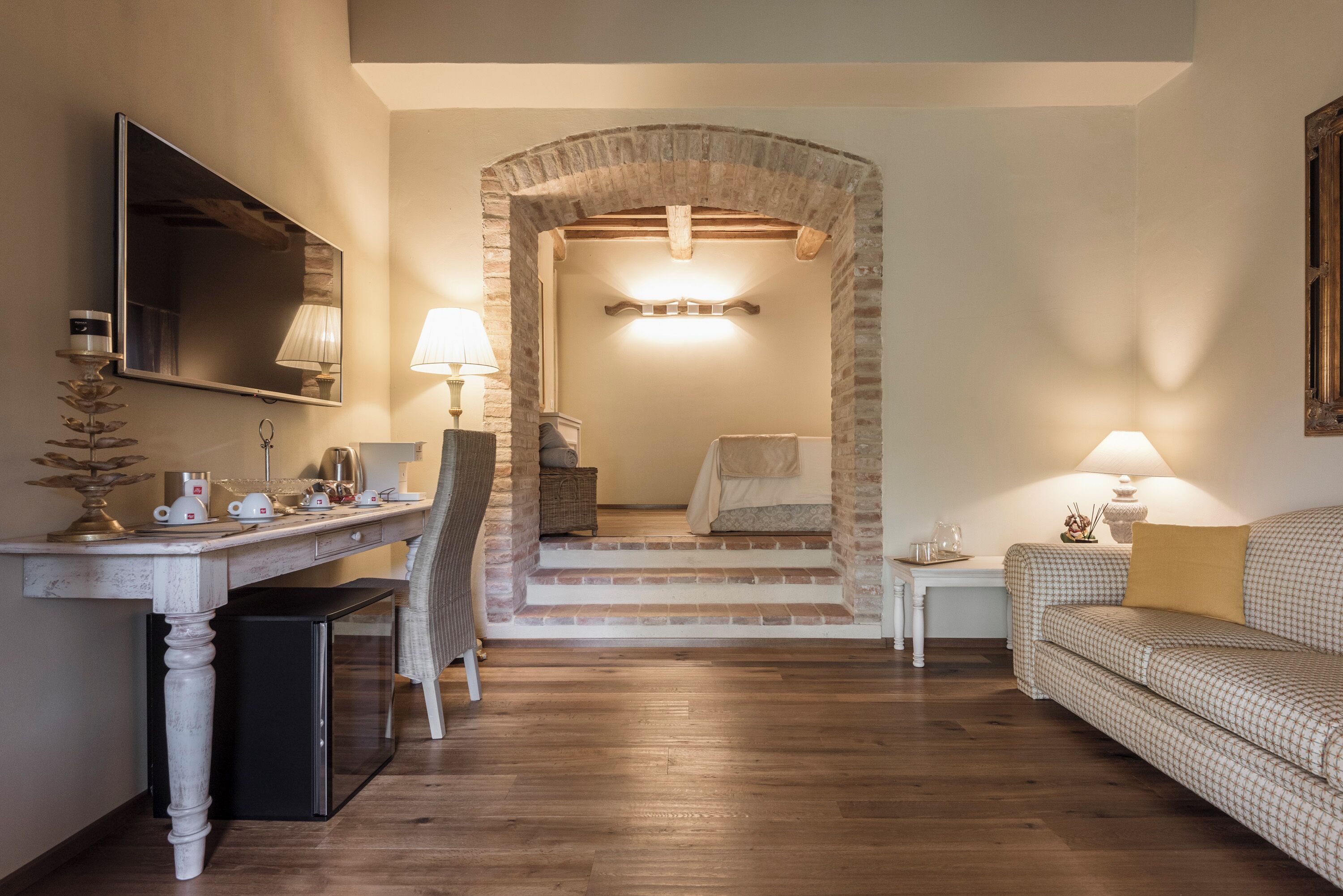 Ein Zimmer mit einem Holztisch, einem Stuhl, einer Couch, einem Fernseher und einer Treppe, die zu einem Schlafzimmer führt.