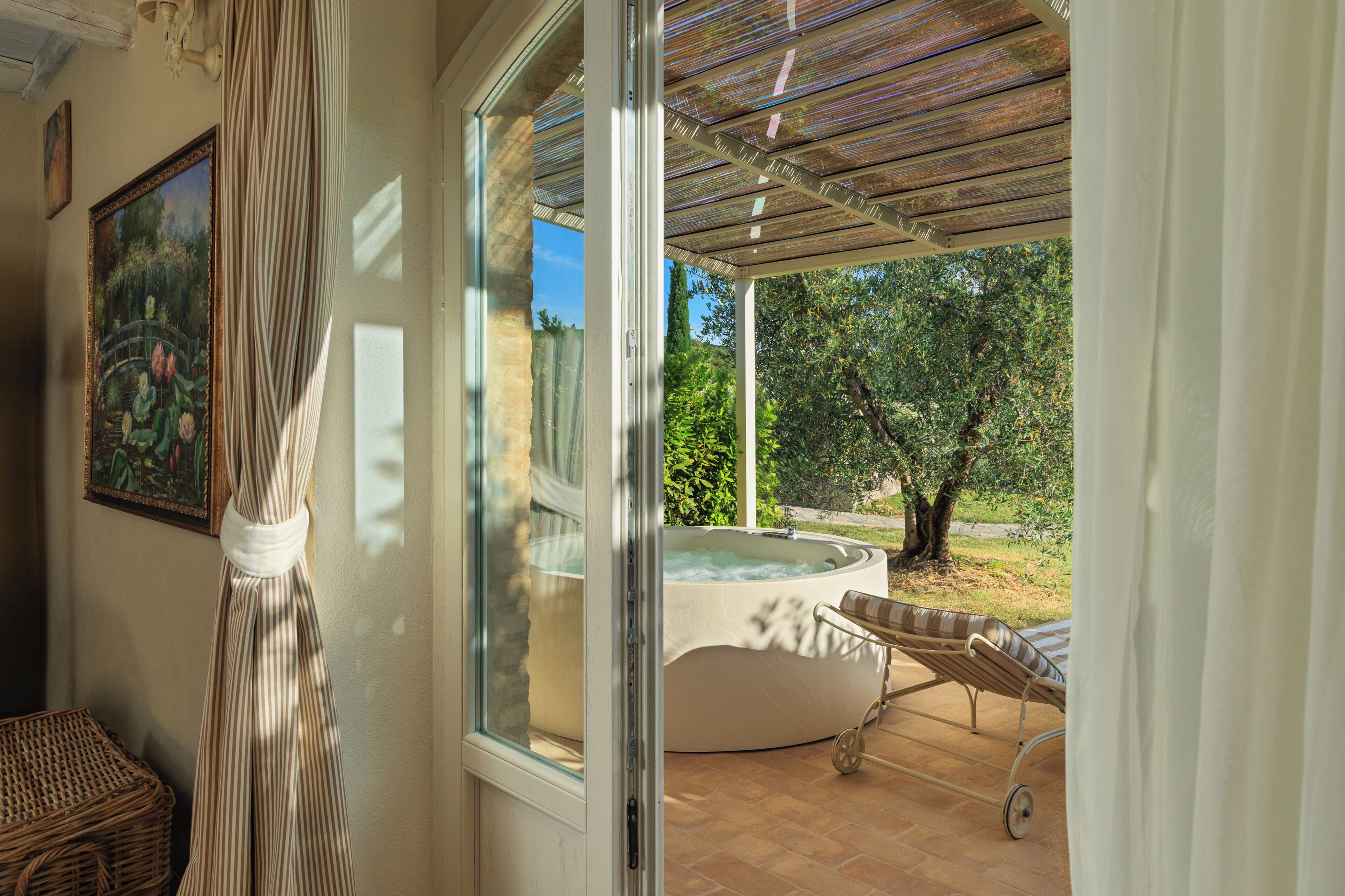 A spa area with a hot tub, a wicker chair, and a view of the garden.