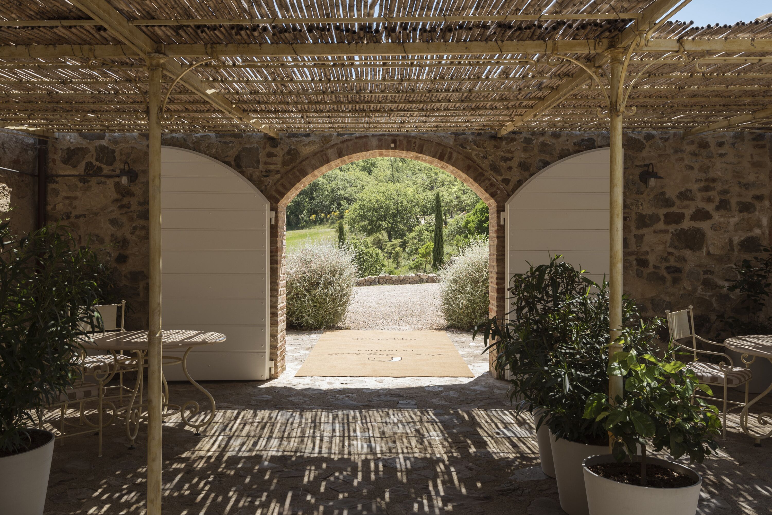 Una terrazza esterna con pergola, pareti in pietra e piante in vaso.