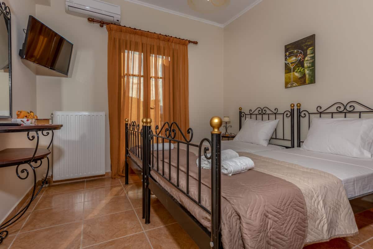 A bedroom with a bed, a bedside table, a TV mounted on the wall, and a window with curtains.