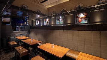 Un interior de restaurante con cabinas, mesas de madera y una barra.